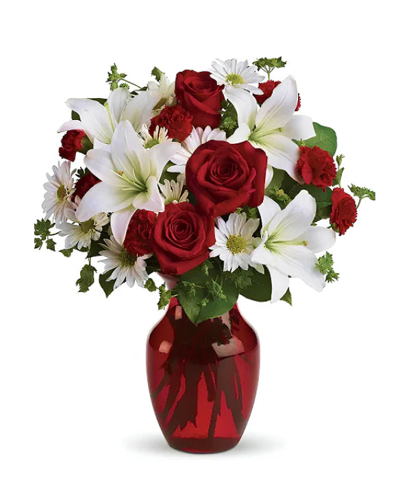 Red roses, white lilies, and daisies in a red vase.